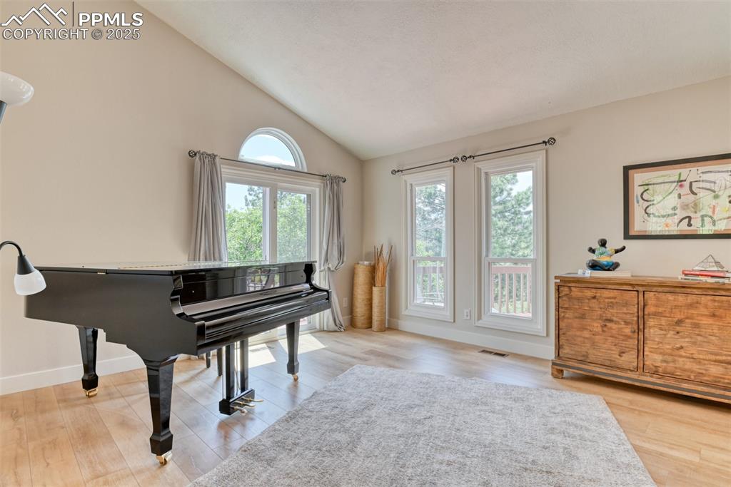Image 7 of 50: Living area featuring wood finished floors, baseboards, and high vaulted ce