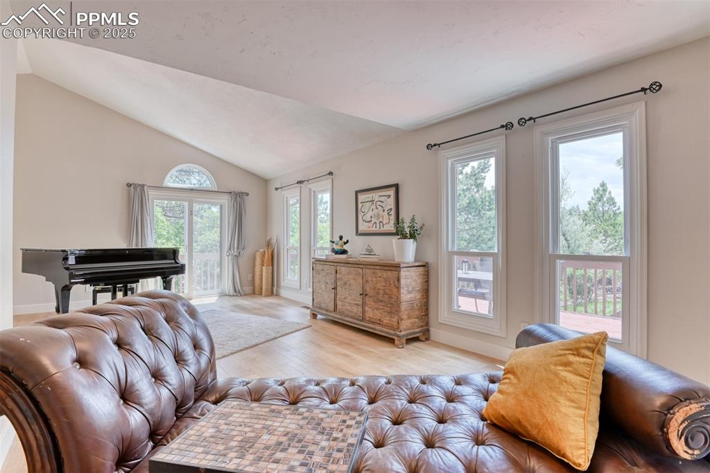 Image 9 of 50: Living area with light wood-style flooring, lofted ceiling, and baseboards
