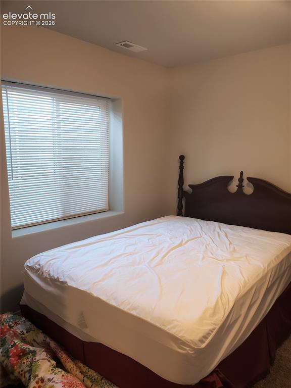 Image 11 of 34: Bedroom featuring neutral wall paint, a window with horizontal blinds, and 