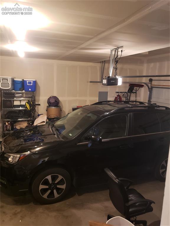 Image 24 of 34: Spacious garage featuring light-toned walls, ceiling-mounted lighting, and 