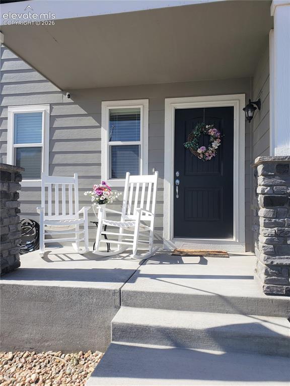 Image 9 of 34: Inviting front porch featuring a dark entry door, light gray siding, and st