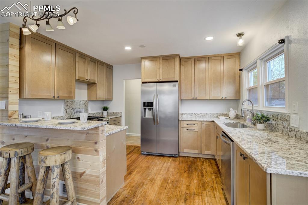 Image 10 of 48: Kitchen with stainless steel appliances, a peninsula, light stone counters,