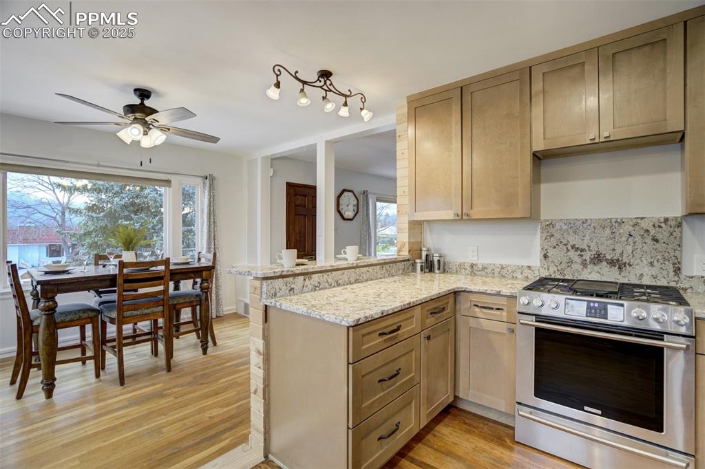 Image 11 of 48: Kitchen featuring gas stove, a peninsula, light wood-style floors, and heal