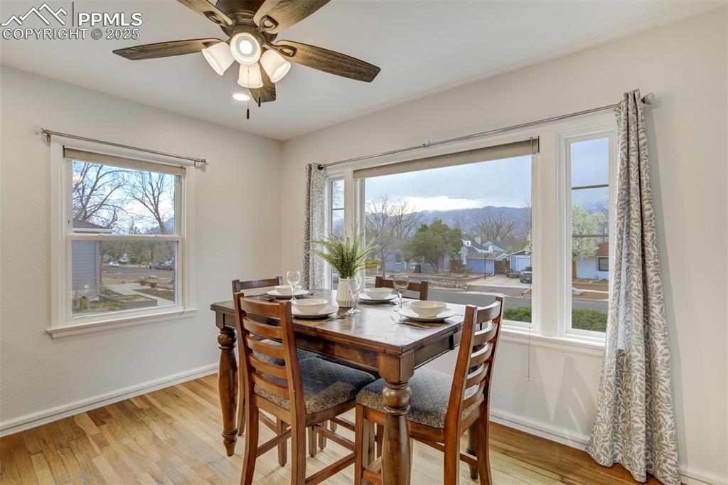 Image 15 of 48: Dining room featuring light wood-type flooring, ceiling fan, and a mountain