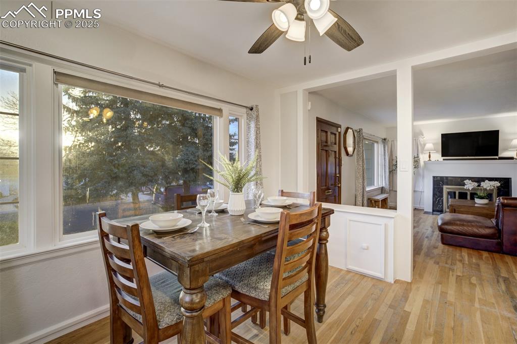 Image 16 of 48: Dining room featuring a tile fireplace, ceiling fan, and light wood-style f