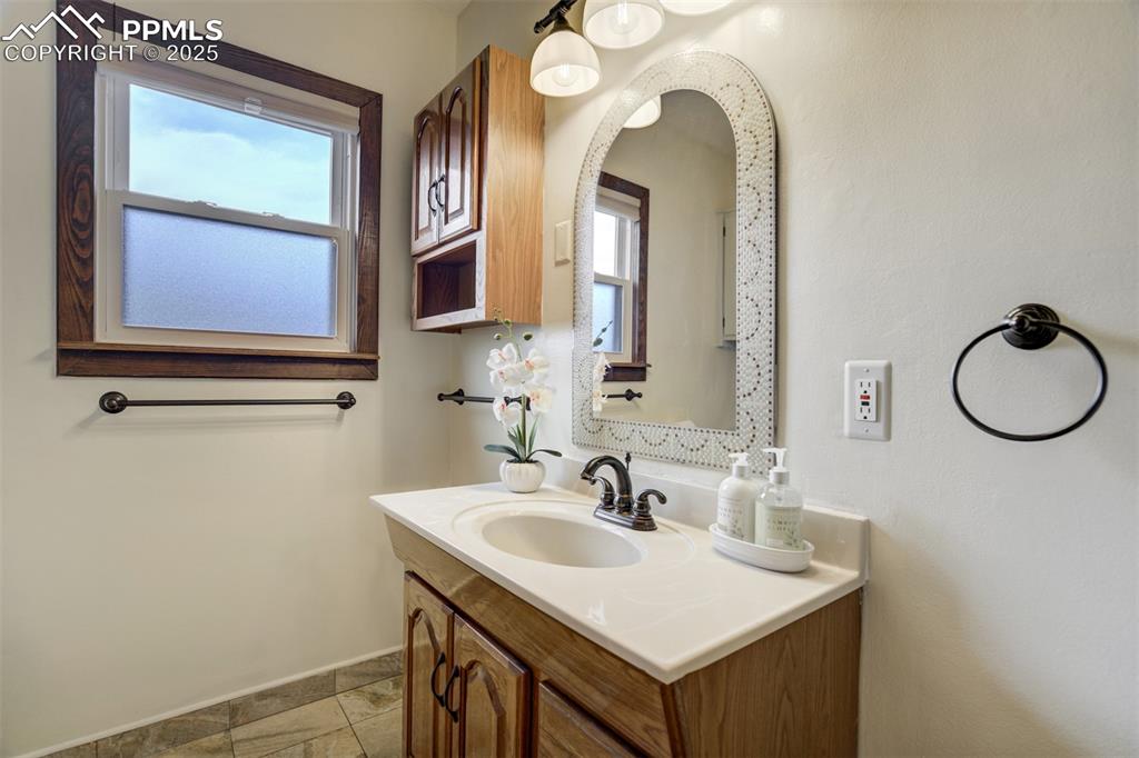 Image 26 of 48: Bathroom with vanity, healthy amount of natural light, and stone finish flo