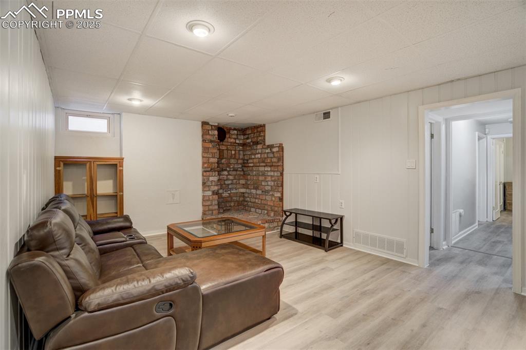 Image 29 of 48: Living room with light wood-type flooring and a paneled ceiling