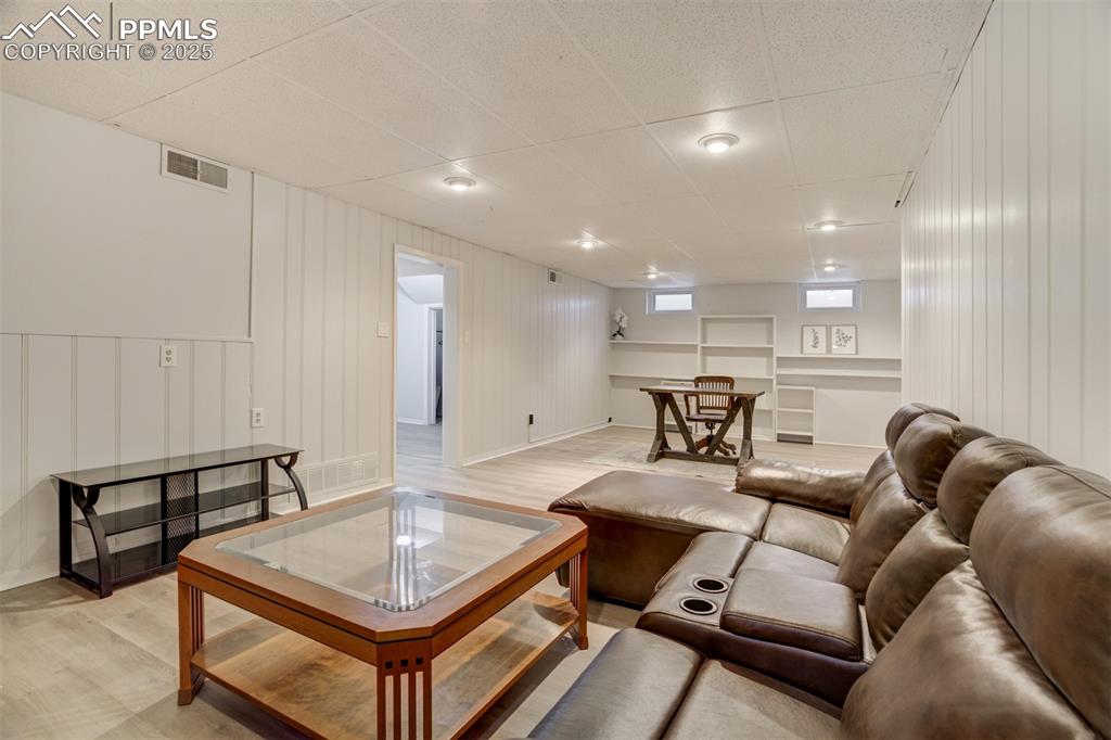 Image 30 of 48: Living room with light wood-type flooring, a decorative wall, and a paneled