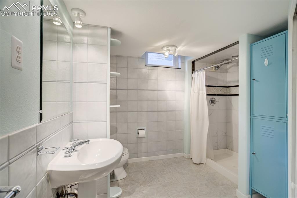 Image 36 of 48: Bathroom with tile walls and a stall shower