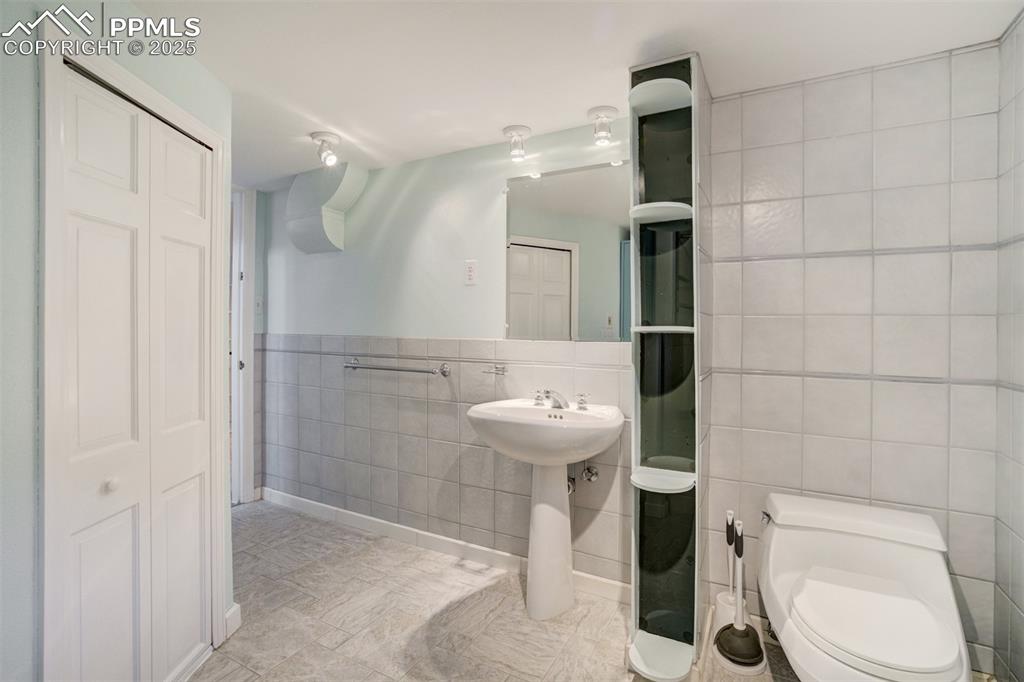 Image 37 of 48: Bathroom featuring tile walls and a closet