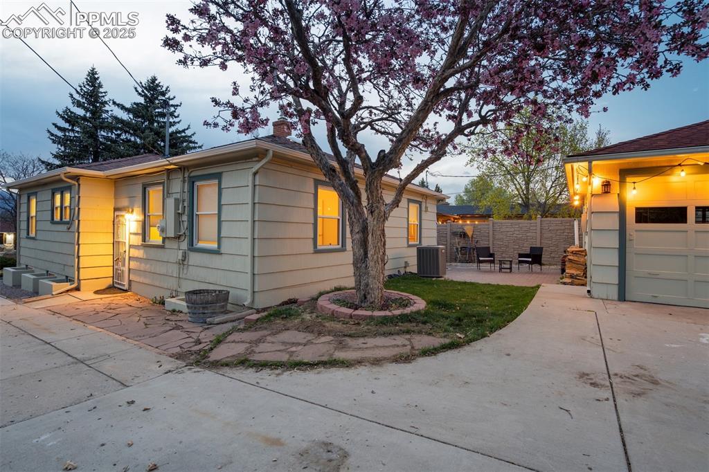 Image 44 of 48: View of side of home with a chimney, concrete driveway, and a patio