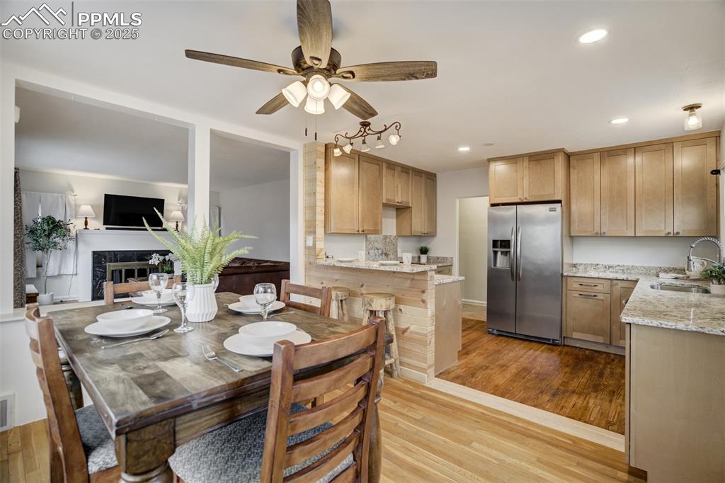 Image 9 of 48: Dining area with a high end fireplace, light wood finished floors, recessed