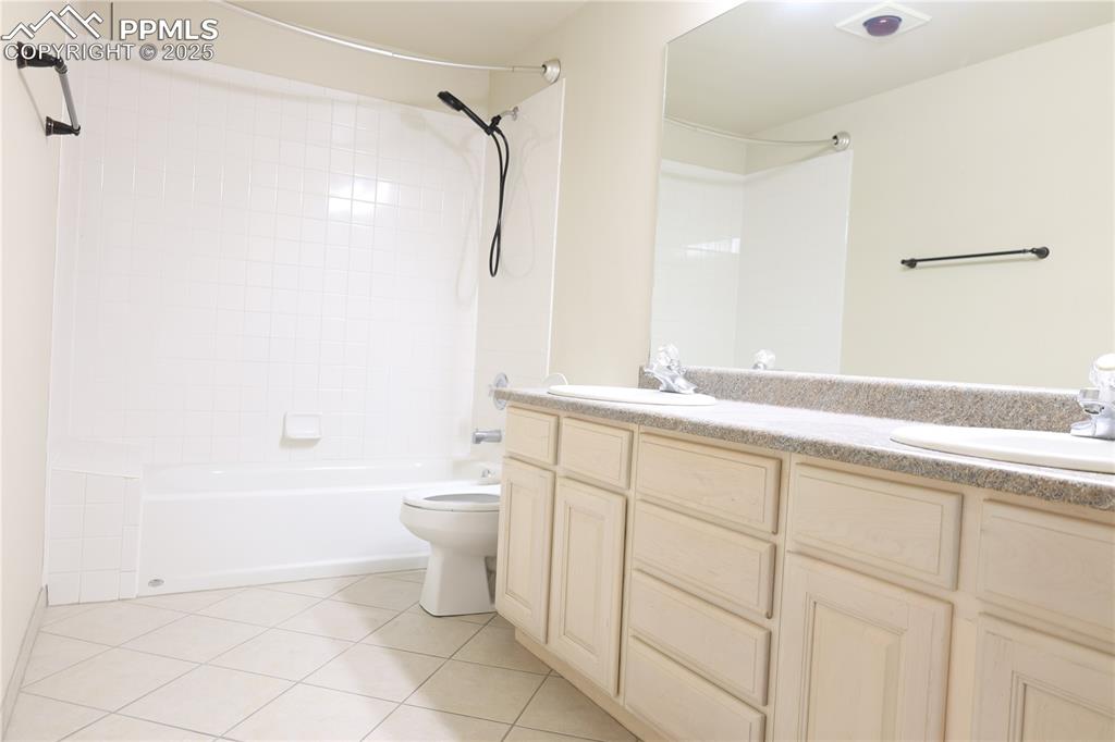 Image 33 of 49: Bathroom with double vanity, light tile patterned floors, and shower / wash