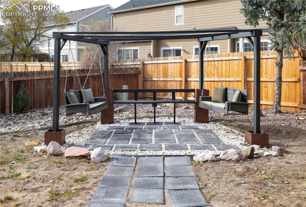 Image 46 of 49: Fenced backyard with a patio