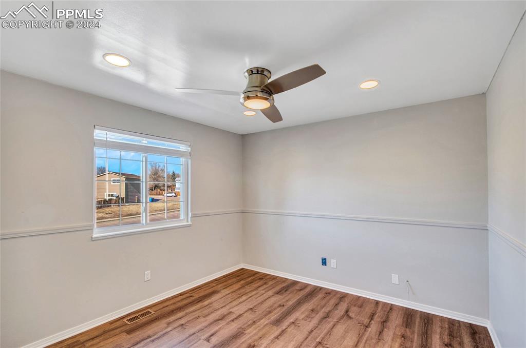 Image 23 of 32: Empty room with ceiling fan and wood-type flooring