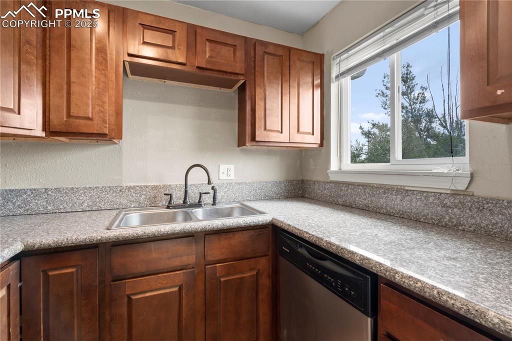 Image 10 of 34: Kitchen featuring dishwasher, brown cabinetry, and light countertops
