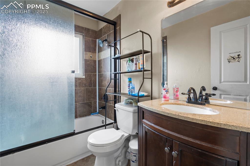 Image 13 of 34: Full bath featuring enclosed tub / shower combo, vanity, and a textured wal