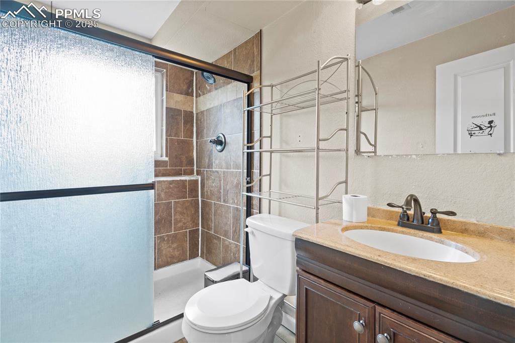 Image 17 of 34: Bathroom with a stall shower, vanity, and a textured wall