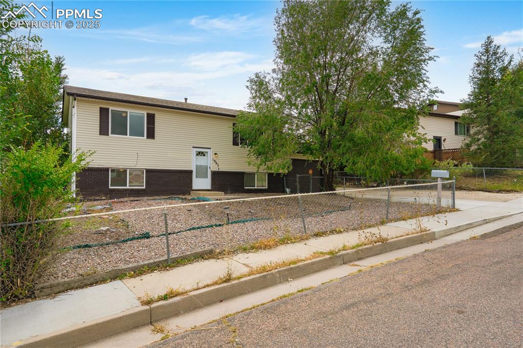 Image 2 of 34: Bi-level home featuring a fenced front yard and brick siding