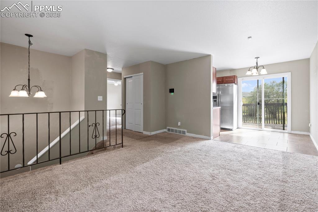 Image 3 of 34: Unfurnished room with a chandelier and light colored carpet