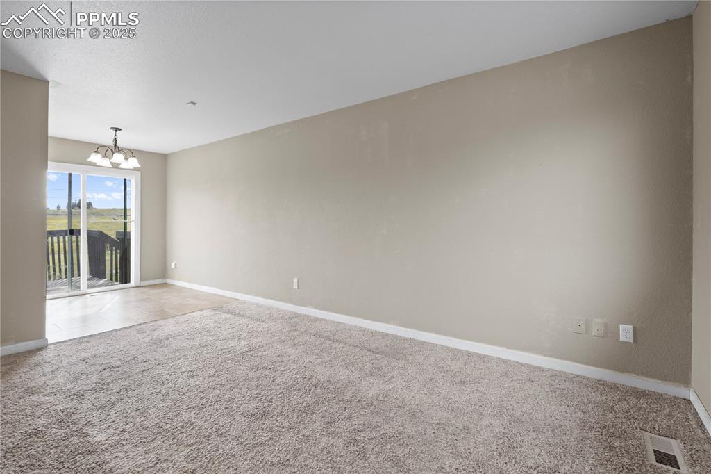 Image 4 of 34: Carpeted empty room featuring a chandelier, tile patterned floors, and a te