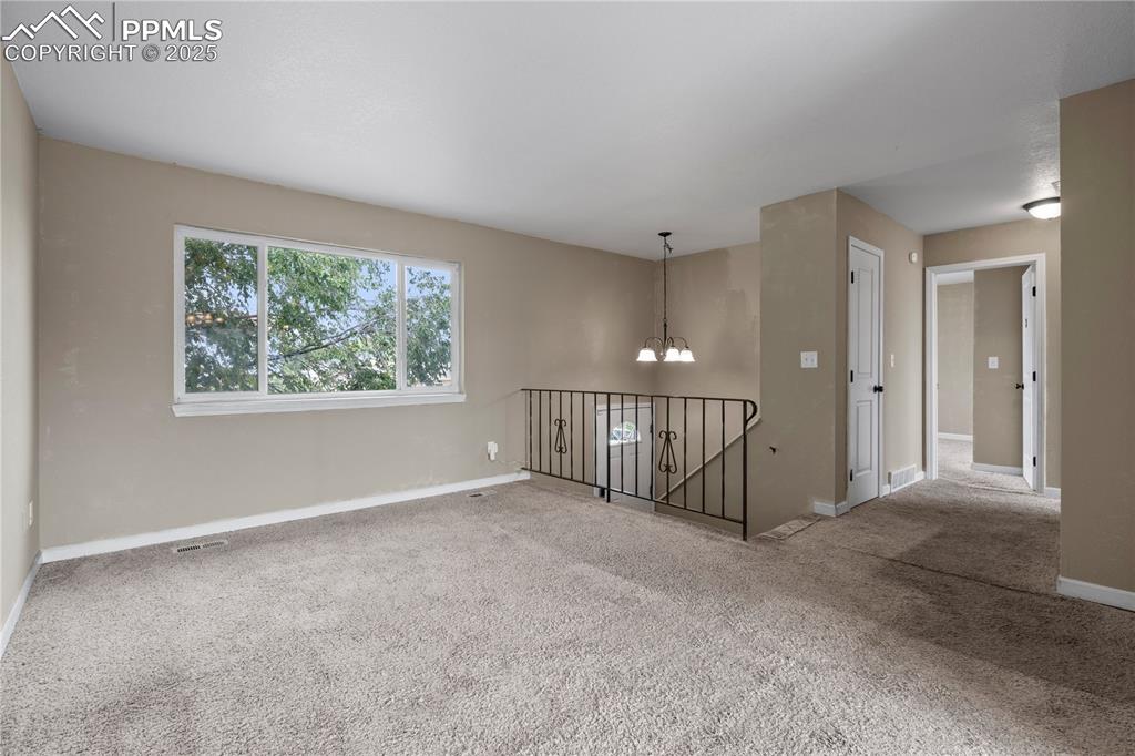 Image 5 of 34: Unfurnished room featuring a chandelier and light colored carpet