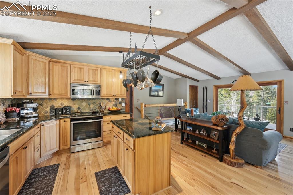 Image 23 of 50: Kitchen with vaulted ceiling with beams, appliances with stainless steel fi