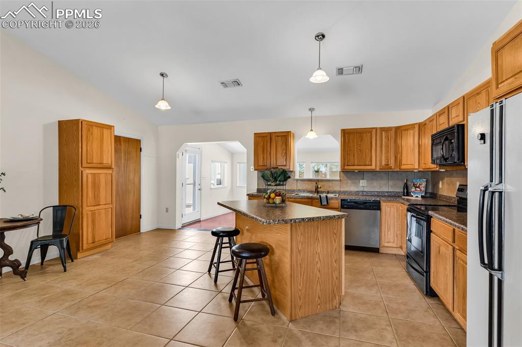 Image 10 of 42: Kitchen with dishwasher, electric stove, black microwave, freestanding refr