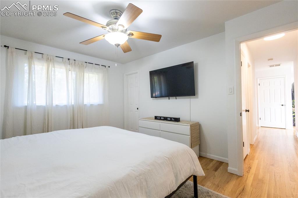 Image 11 of 27: Bedroom with light wood finished floors and ceiling fan