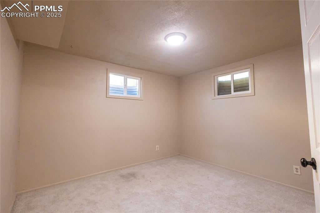 Image 18 of 27: Basement with a textured ceiling and carpet