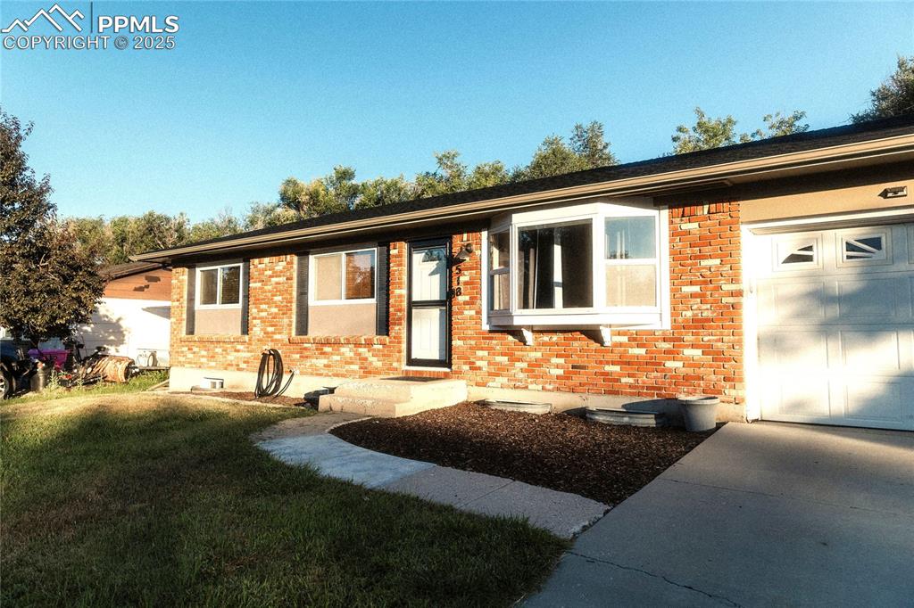 Image 2 of 27: Ranch-style home with brick siding, an attached garage, a front lawn, and d