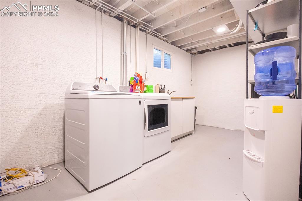 Image 20 of 27: Washroom featuring a textured wall and washing machine and clothes dryer