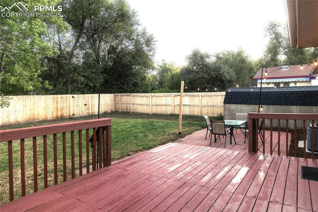 Image 22 of 27: Wooden terrace featuring outdoor dining area, a fenced backyard, and view o