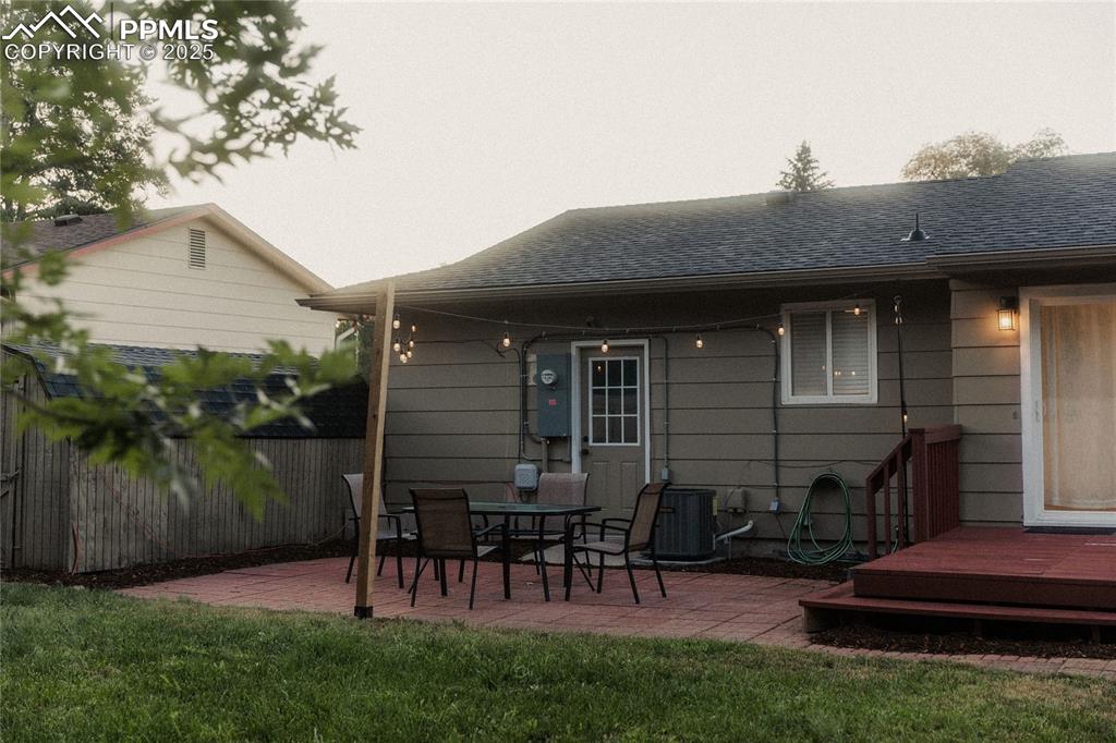 Image 25 of 27: Rear view of house featuring roof with shingles, a wooden deck, and a patio