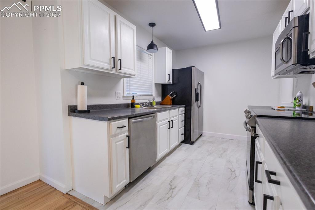 Image 5 of 27: Kitchen featuring dark countertops, appliances with stainless steel finishe