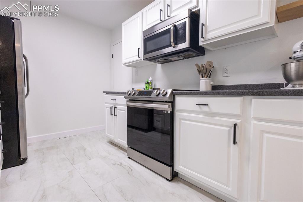 Image 6 of 27: Kitchen with stainless steel appliances, light marble finish flooring, and 