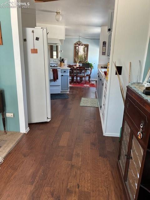 Image 16 of 30: Kitchen with stainless steel appliances, dark wood-style flooring, white ca