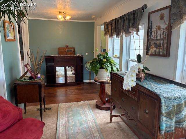 Image 20 of 30: Sitting room with dark wood-style flooring, ornamental molding, and a textu