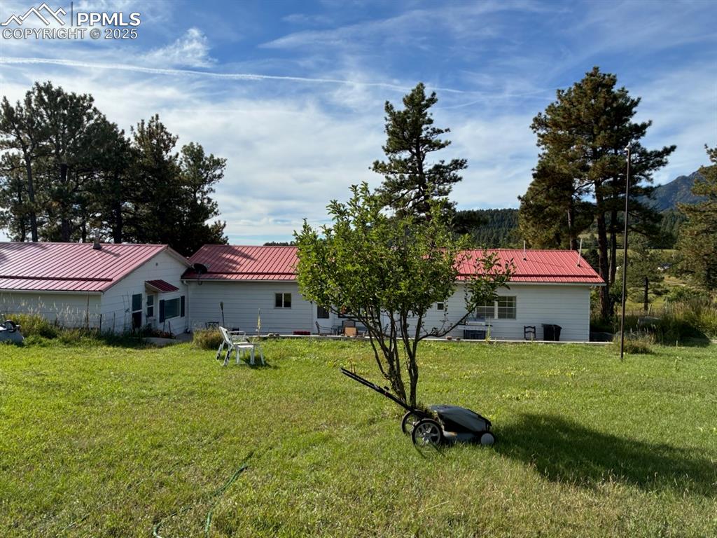 Image 29 of 30: Back of house with a metal roof and a yard