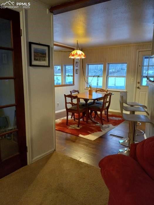 Image 4 of 30: Carpeted dining space featuring baseboards and wood finished floors