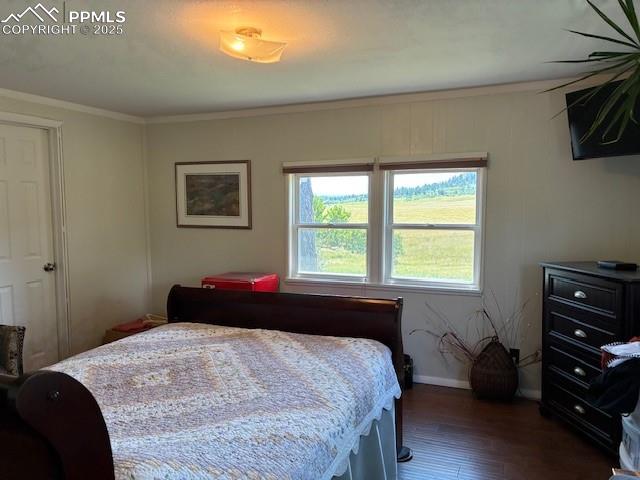Image 8 of 30: Bedroom with dark wood finished floors and crown molding