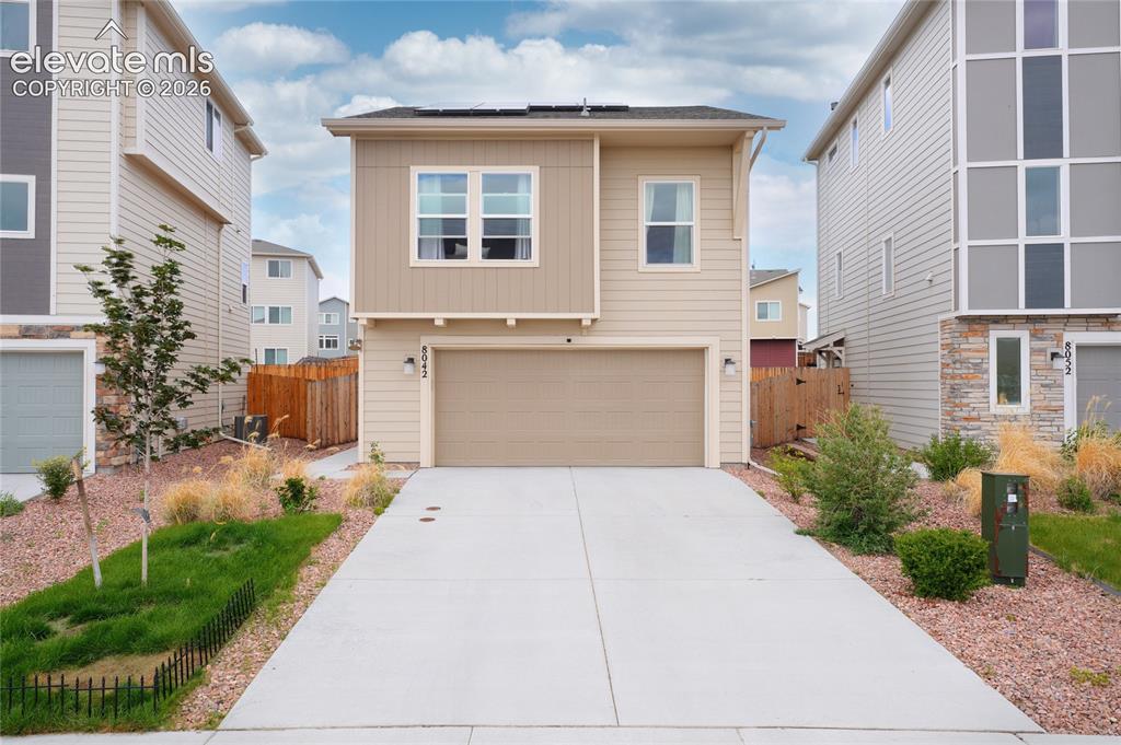 Caption: Contemporary two-story residence featuring a two-car garage and a concrete driveway
