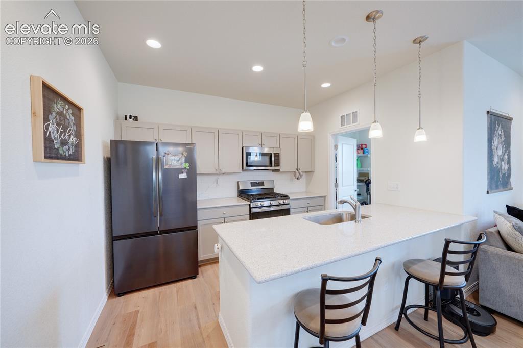 Image 12 of 21: Modern kitchen with light wood-finish flooring and recessed lighting