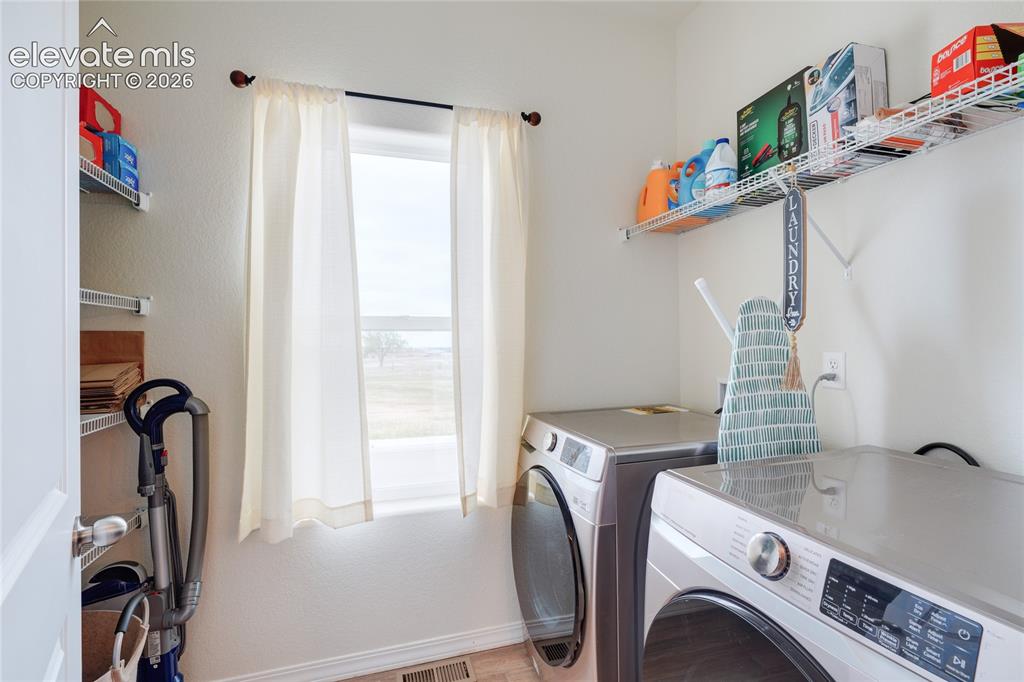 Image 14 of 21: Dedicated laundry area featuring a window, overhead shelving, and wood-fini