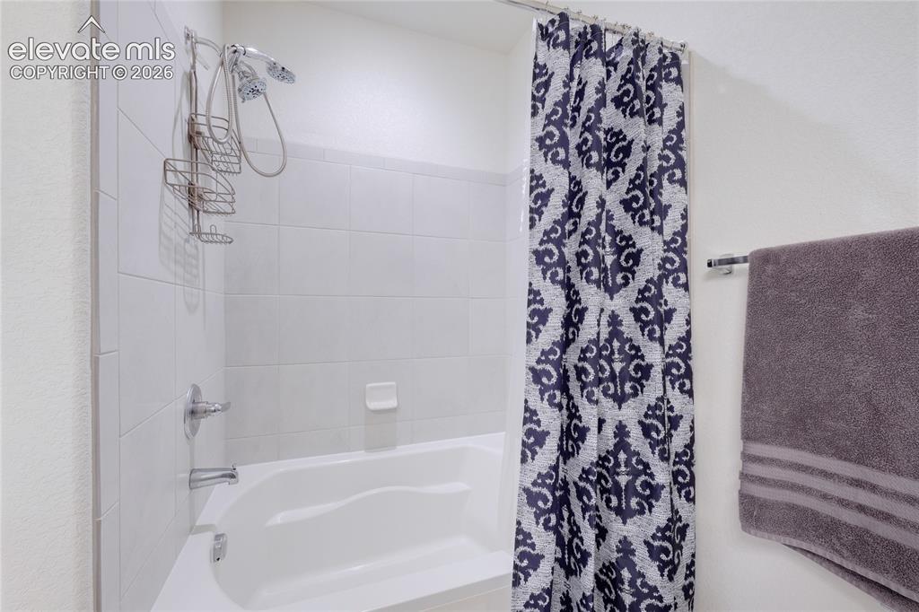 Image 17 of 21: Tub and shower combination featuring white subway tile surround and chrome 