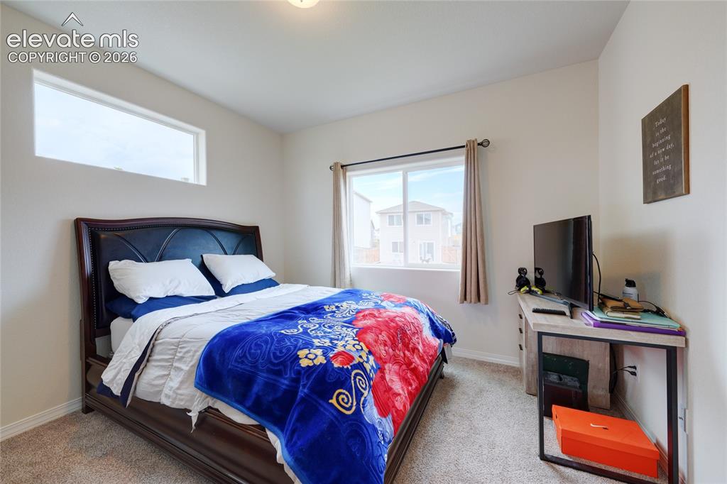 Image 18 of 21: Carpeted bedroom featuring a large window, a transom window, and neutral wa