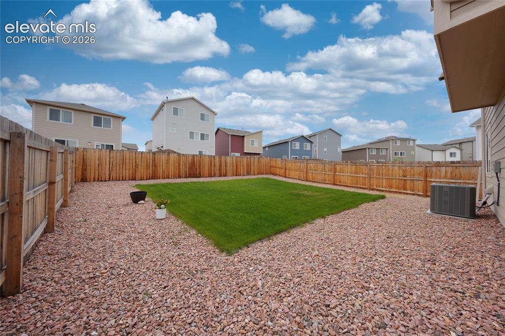 Image 20 of 21: Fully fenced backyard featuring a central lawn area, surrounding gravel lan