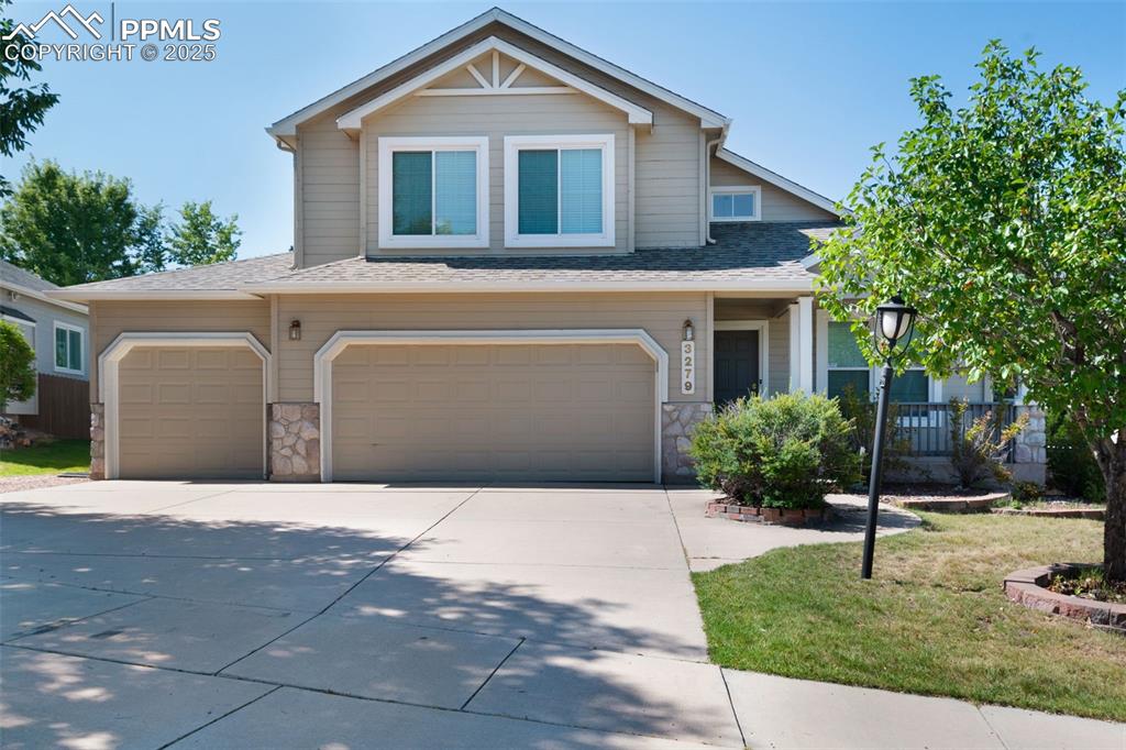Caption: View of front of home with stone siding, concrete driveway, a shingled roof, an attached garage, and