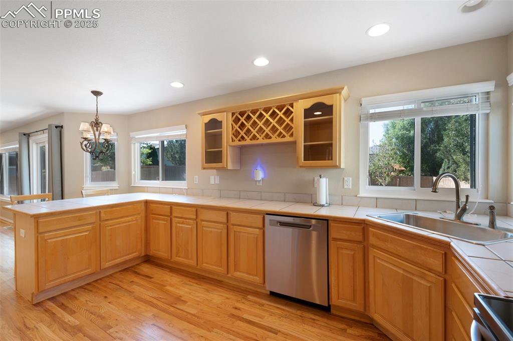 Image 11 of 37: Kitchen with decorative light fixtures, tile countertops, appliances with s