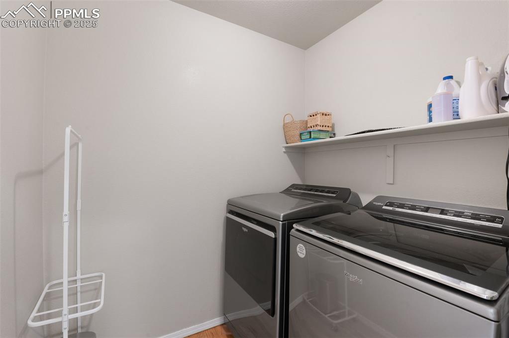 Image 17 of 37: Washroom featuring washing machine and clothes dryer and light wood-style f
